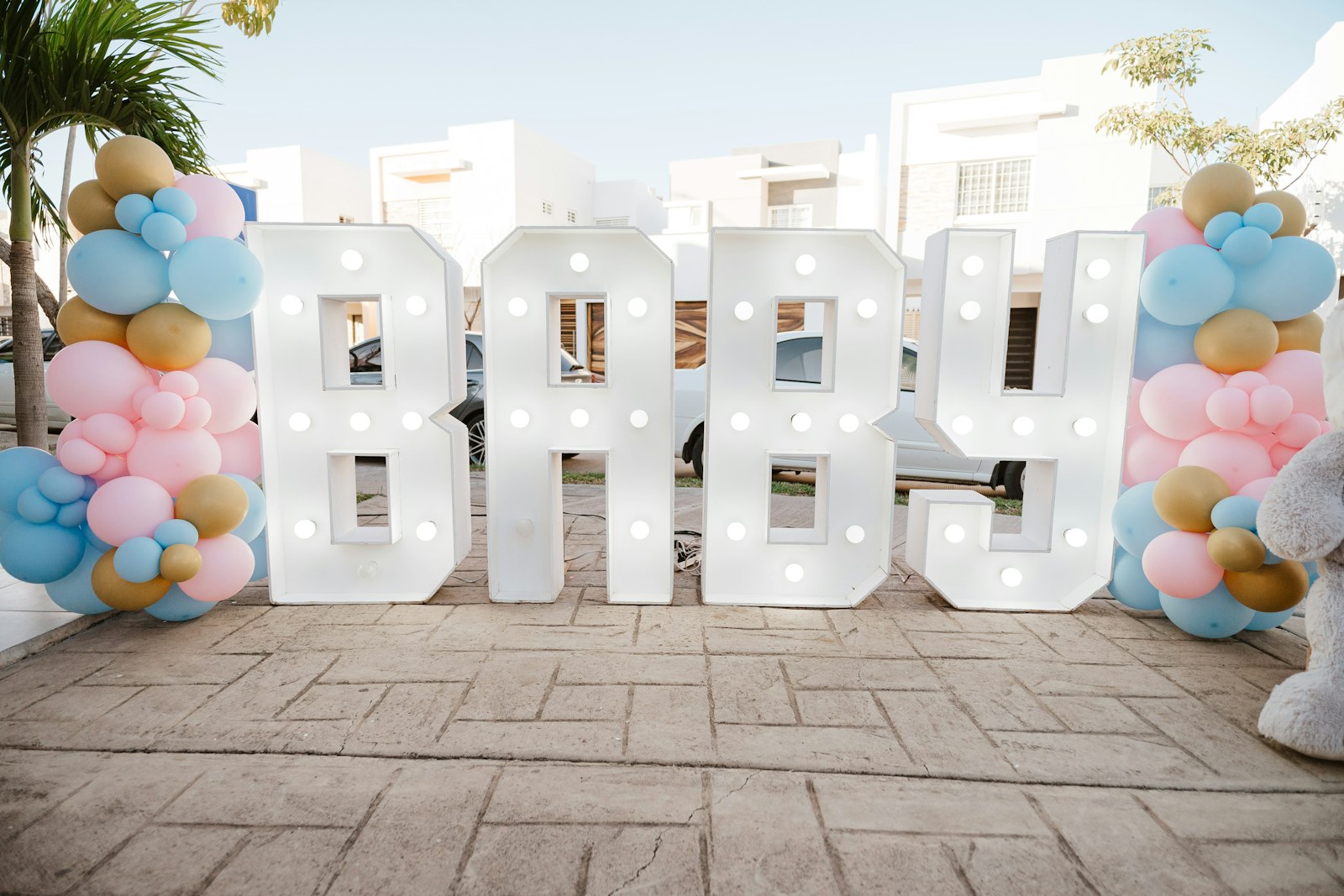 Light-up BABY marquee letters in front of pastel blue, pink and gold balloon columns